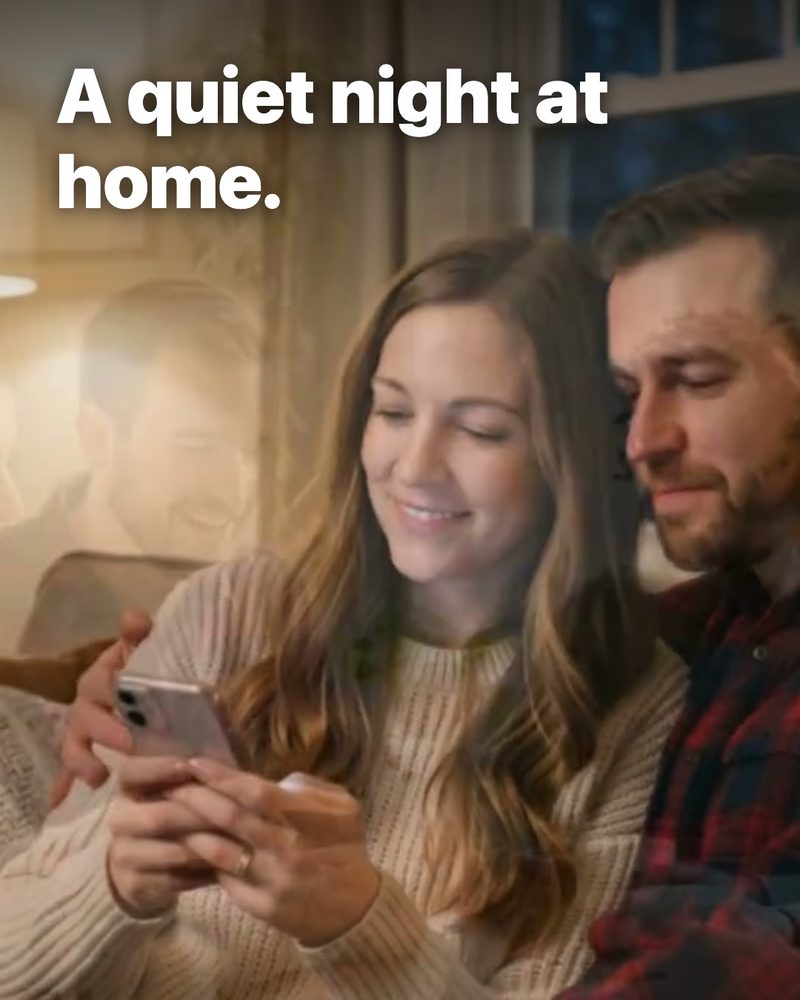 A couple on a sofa looking at a phone in warm lamplight, with the words A quiet night at home. on it (sample)
